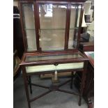 A Edwardian display cabinet with cross band inlay on square tapering legs on peg feet .