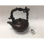A Chinese terracotta tea pot the handle with raised figures.