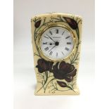 A Moorcroft clock with floral decoration on an ivory coloured ground, approx height 15.5cm.