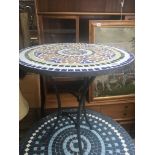 A garden table of circular shape with a mosaic top