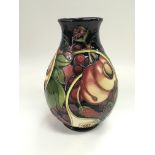 A Moorcroft trial vase by Emma Bosson depicting various fruit on a blue ground, approx height 19cm.