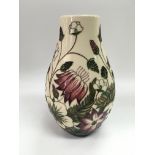 A Moorcroft vase decorated with various flowers on an ivory ground, approx height 23.5cm.