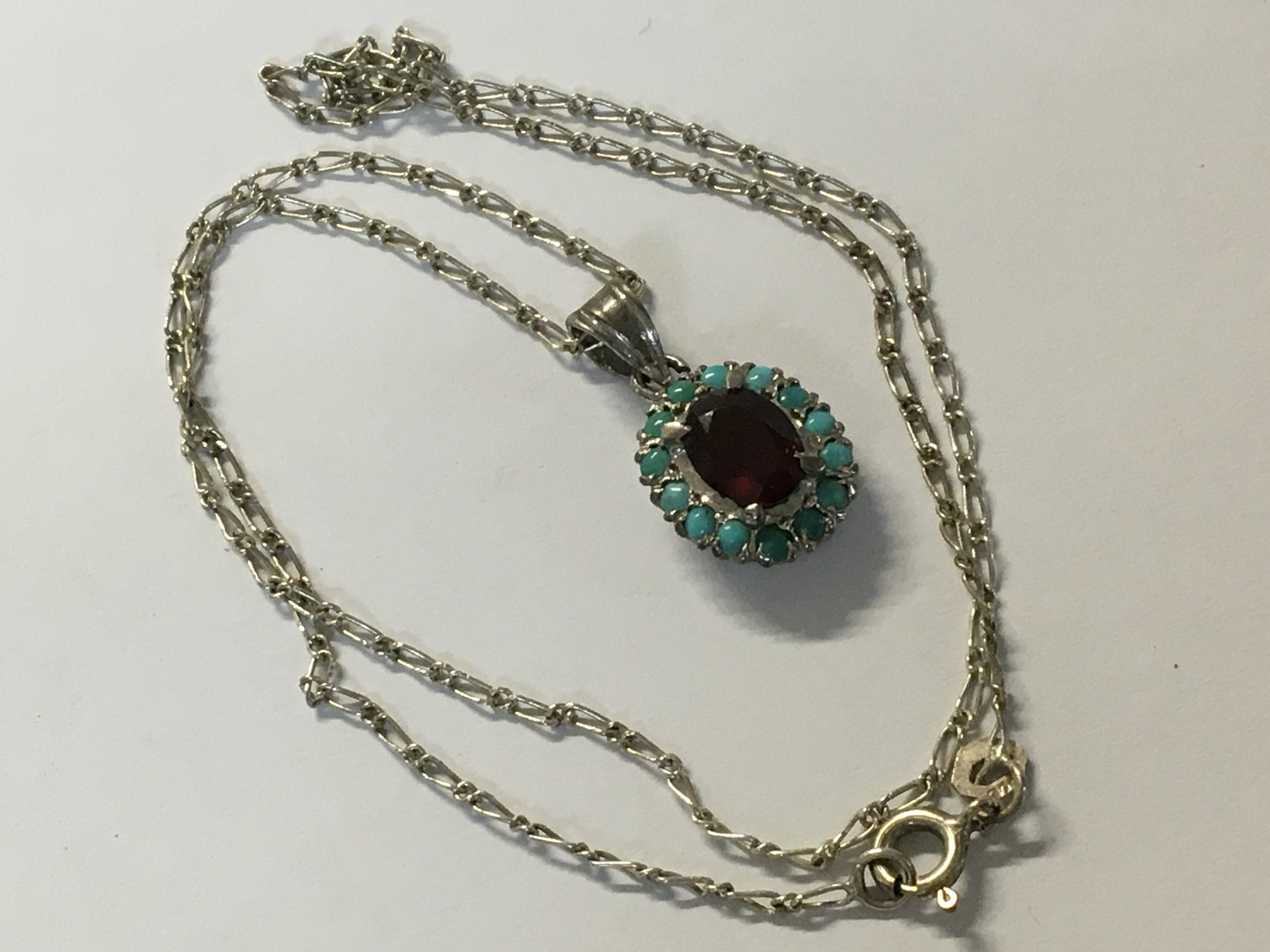 A turquoise and garnet pendant on attached silver