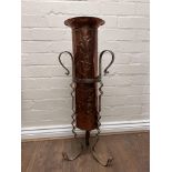 An arts and crafts copper stick stand with a wroug