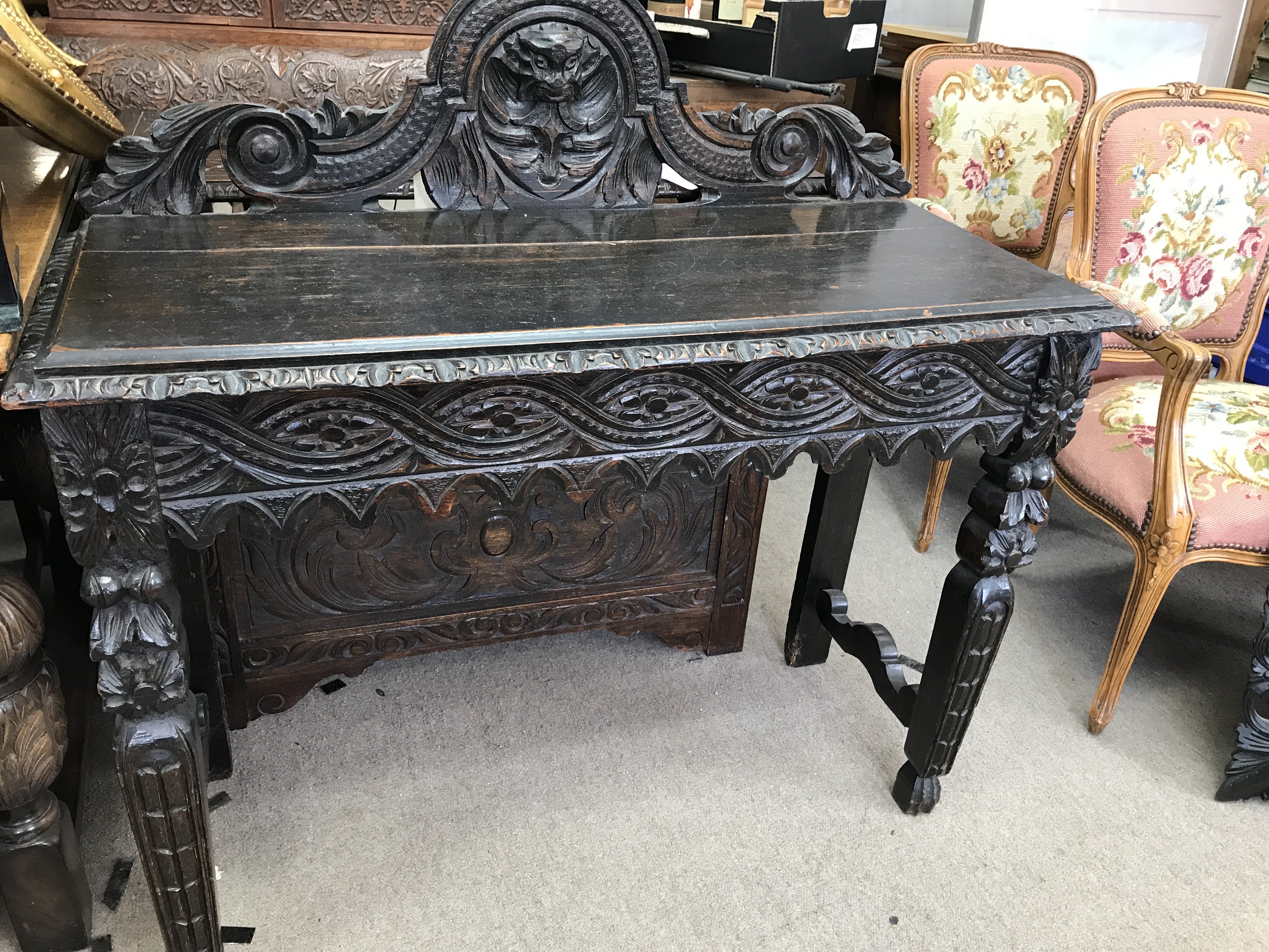 A carved oak side table, the raised back above car