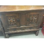 A small carved oak cabinet the cupboard doors with
