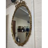 A gilt gramed oval mirror with scroll top, approx