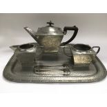 An Arts & Crafts hammered pewter four piece tea se