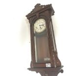 A Continental mahogany wall clock with a visible pendulum.