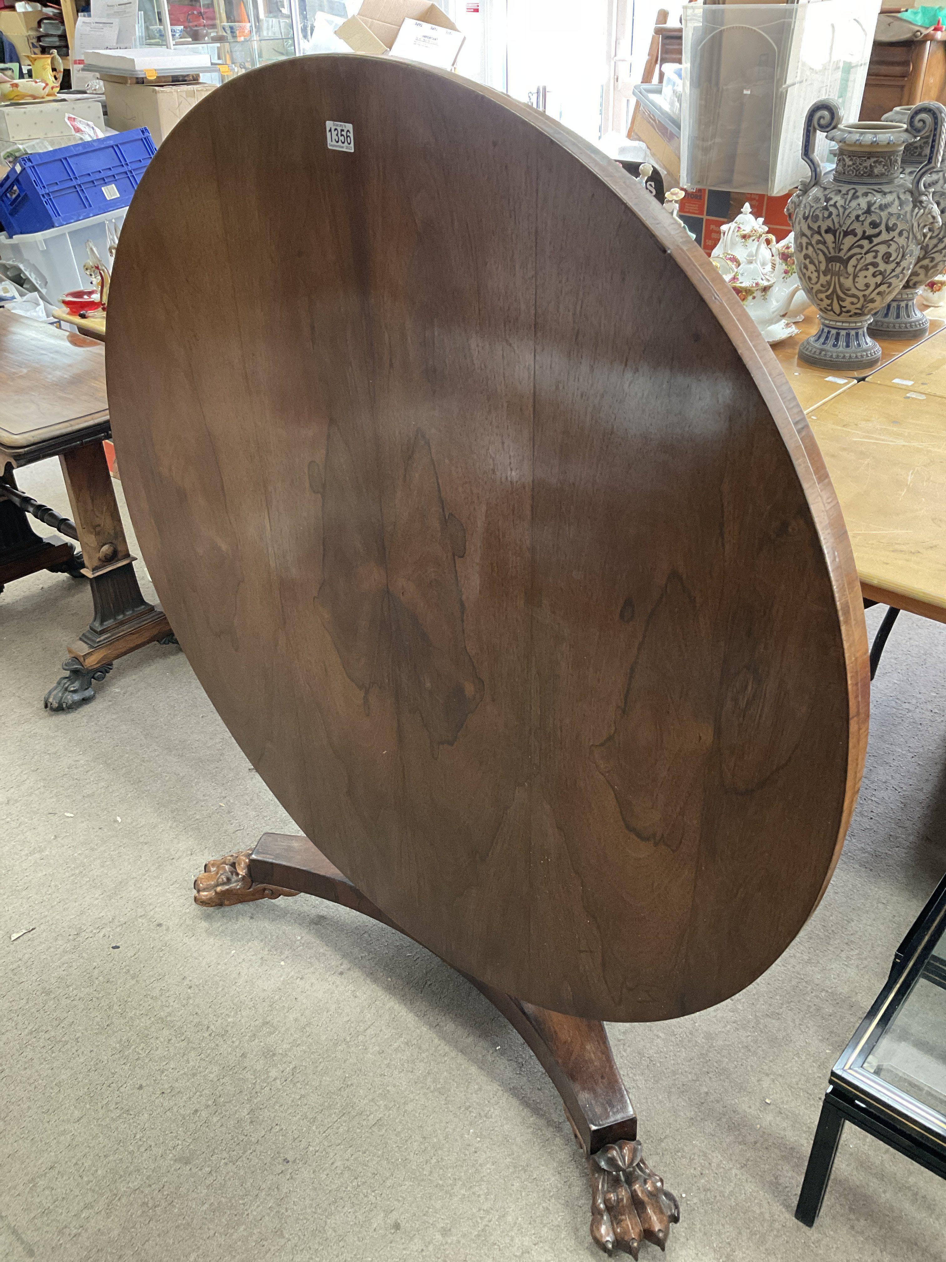 A circular rosewood dining table with lions paw feet and 4 red rosewood upholstered dining chairs.