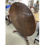 A circular rosewood dining table with lions paw feet and 4 red rosewood upholstered dining chairs.