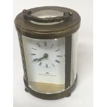 A round brass carriage clock by Mathew Norman. The