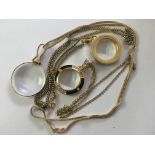 Three gold coloured magnifying glasses on chains