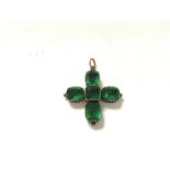 An antique gold cross set with green stones.