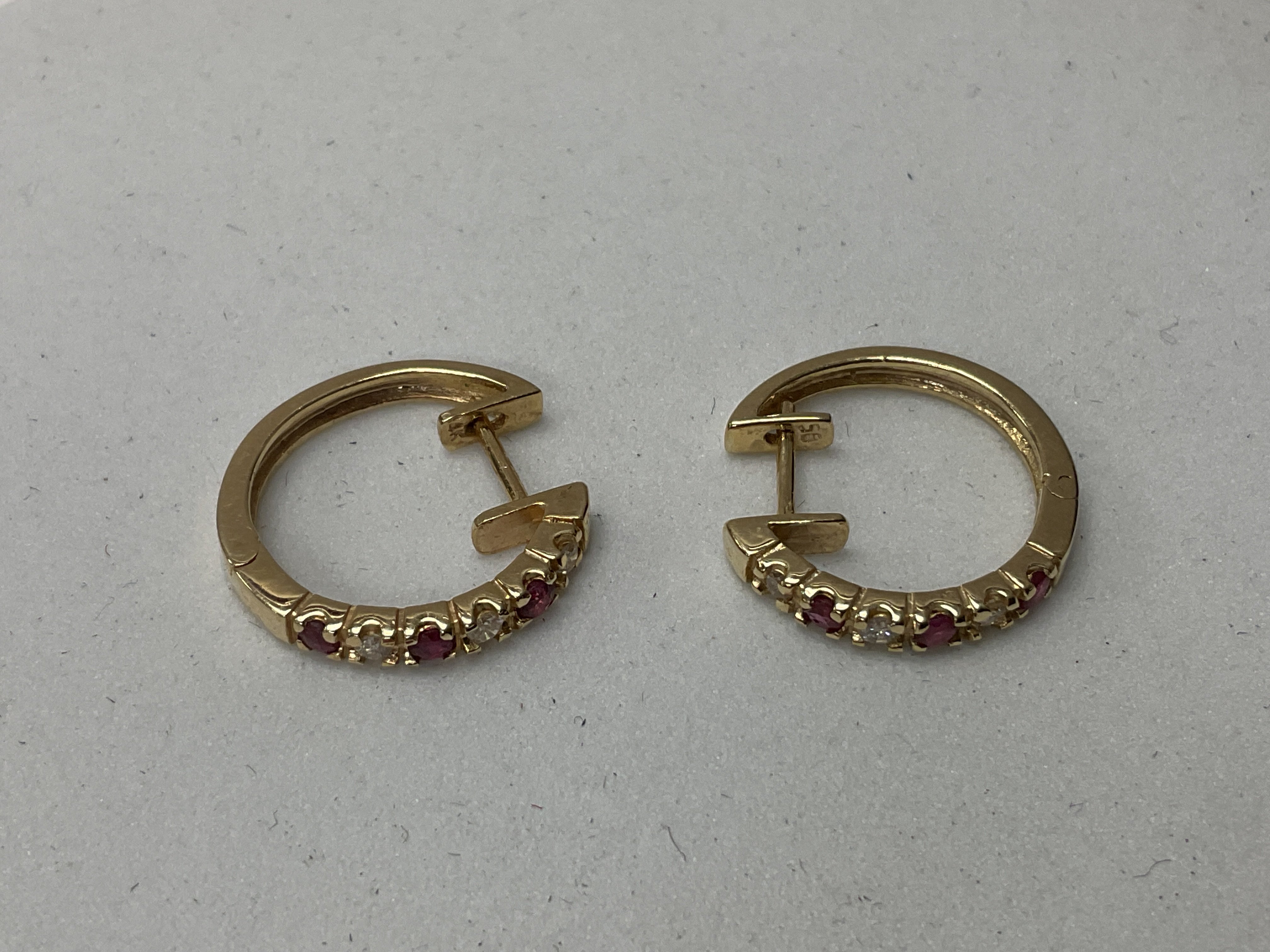 A pair of 14K ruby and diamond hoop earrings.