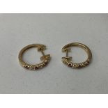 A pair of 14K ruby and diamond hoop earrings.