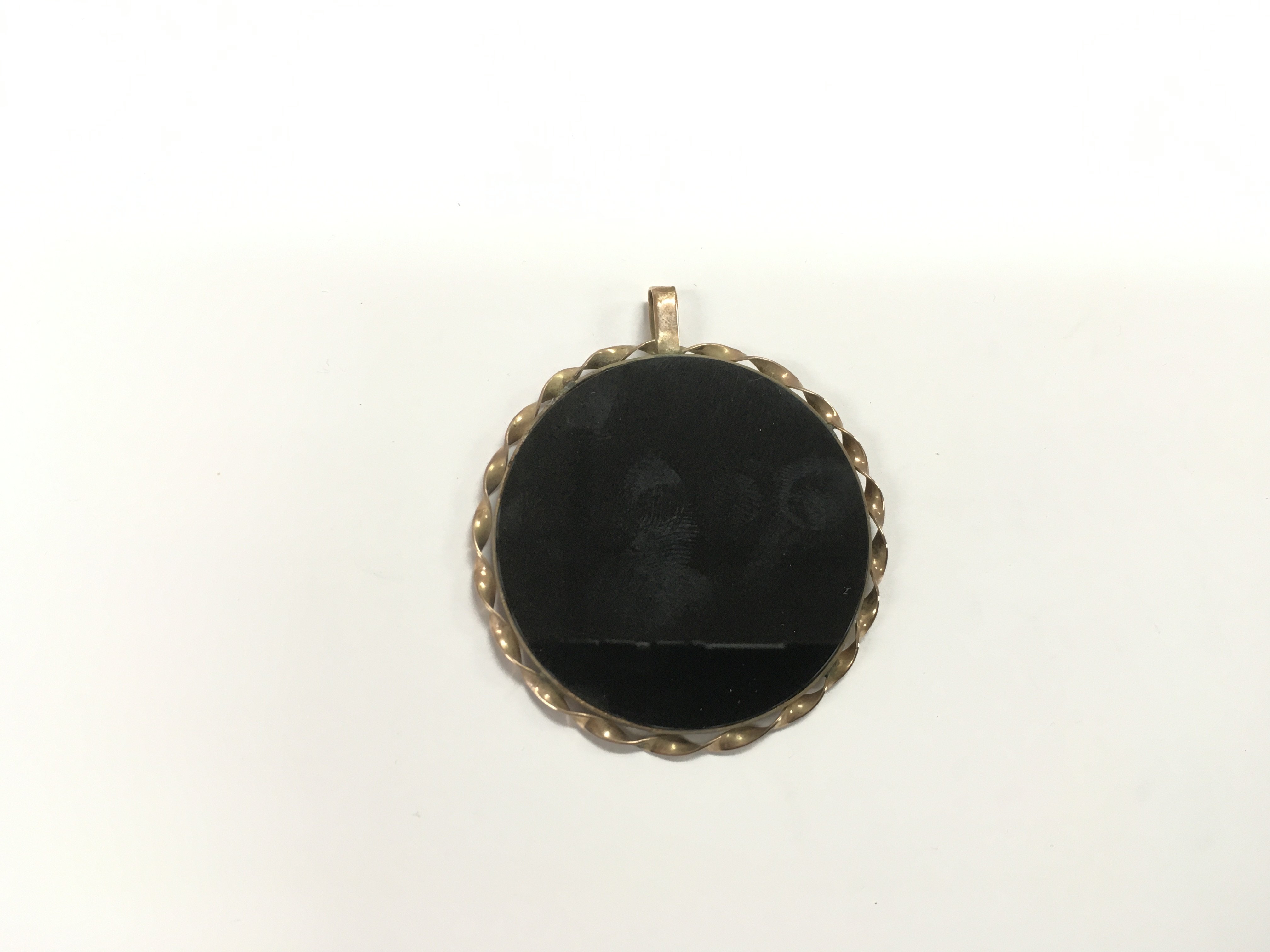 An unmarked gold and polished stone circular penda