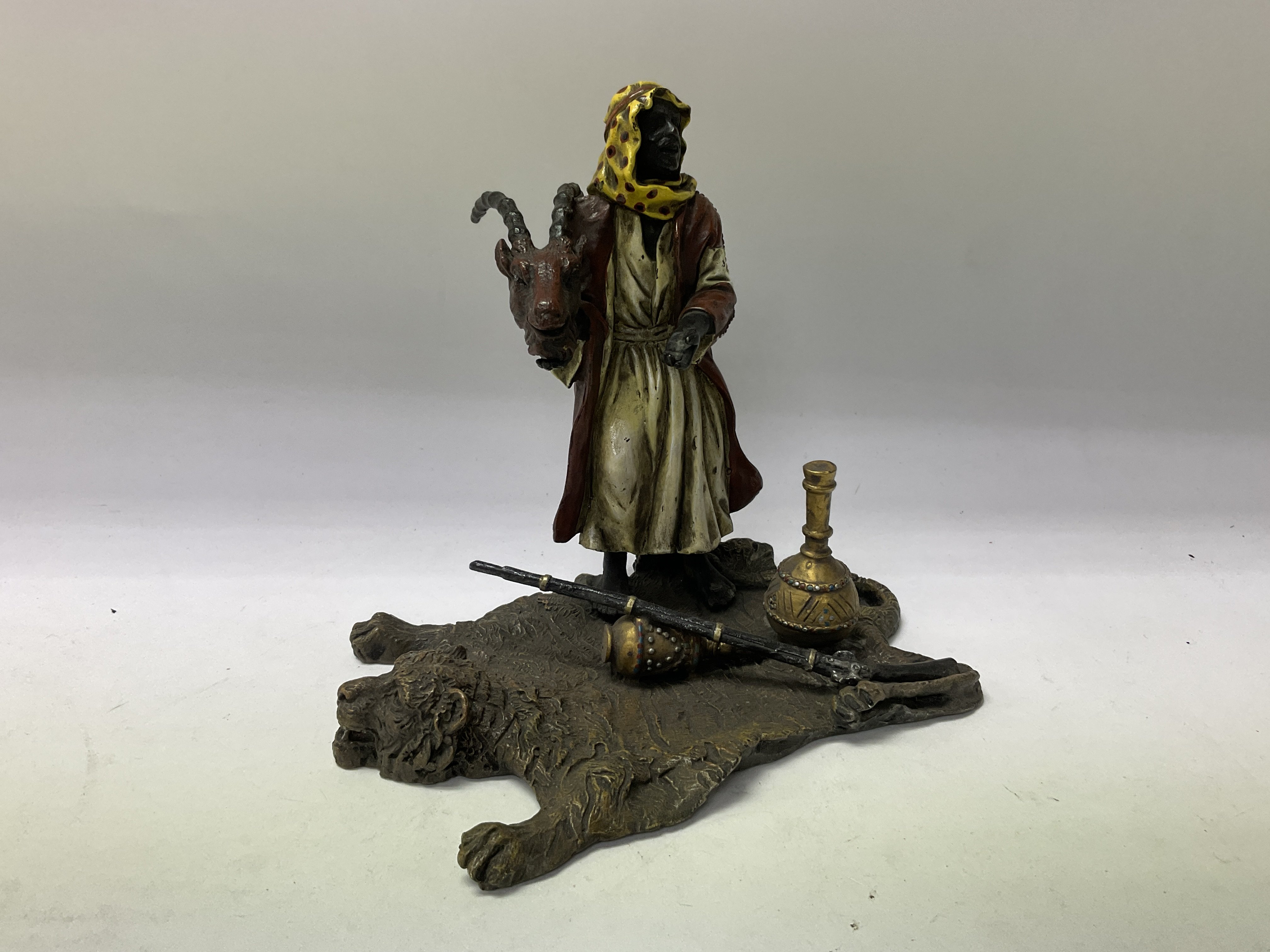 A cold painted bronze Arab figure holding a rams h
