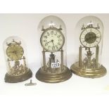 Three brass anniversary clocks under glass domes (
