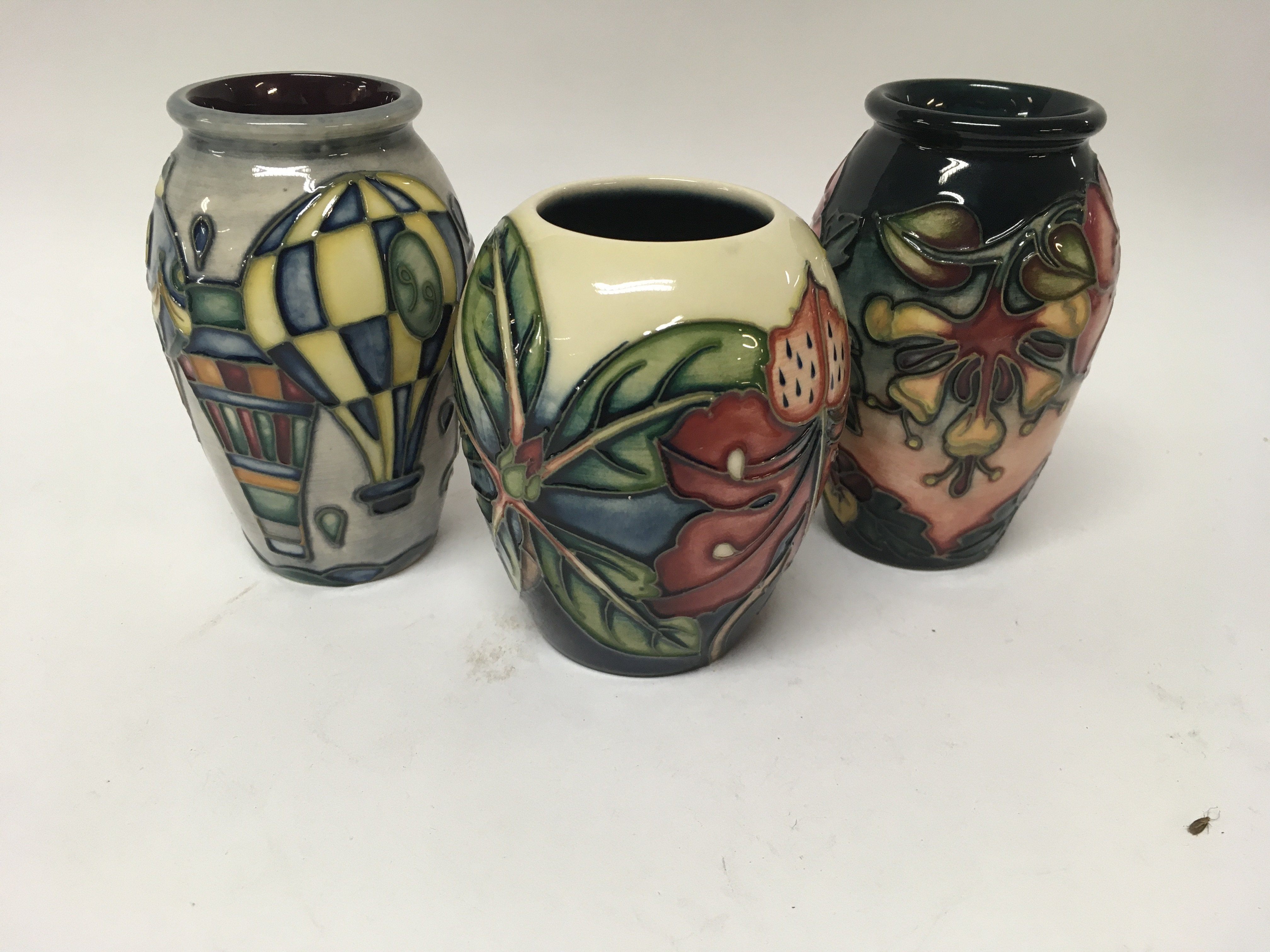 Three Moorcroft vases decorated with flowers and f