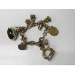 A gold bracelet with attached charms including sov