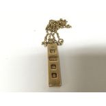 A 9carat gold ingot type pendent with attached cha