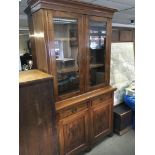 An Edwardian walnut bookcase cupboard with glazed doors above two drawers and cupboards under.