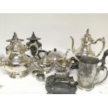 A collection of silver plate tea and coffee sets a pen stand a pair of urns and covers.