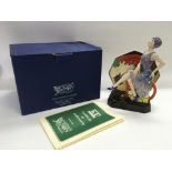 A boxed Peggy Davies ceramic figure of an Art Deco maiden seated amongst Clarice Cliff style