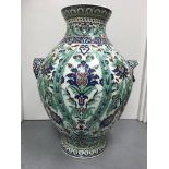 A large twin handled Iznik bulbous vase decorated in traditional style, with flowers and foliage.