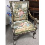 An Early 18th century style open arm chair with gilded scroll arms and legs and a tapestry covered