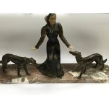 An Art Deco figural group of a lady with two dogs at her side nad raised in a marble base, approx