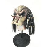 A Latex Predator Movie Film Prop on a Stand. Appro