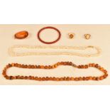 A 9ct gold ring set with a pressed amber cabochon, amber necklace, three strand pearl necklace,