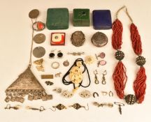 A collection of jewellery including carved ivory pendant, white metal pot, embossed brooch depicting