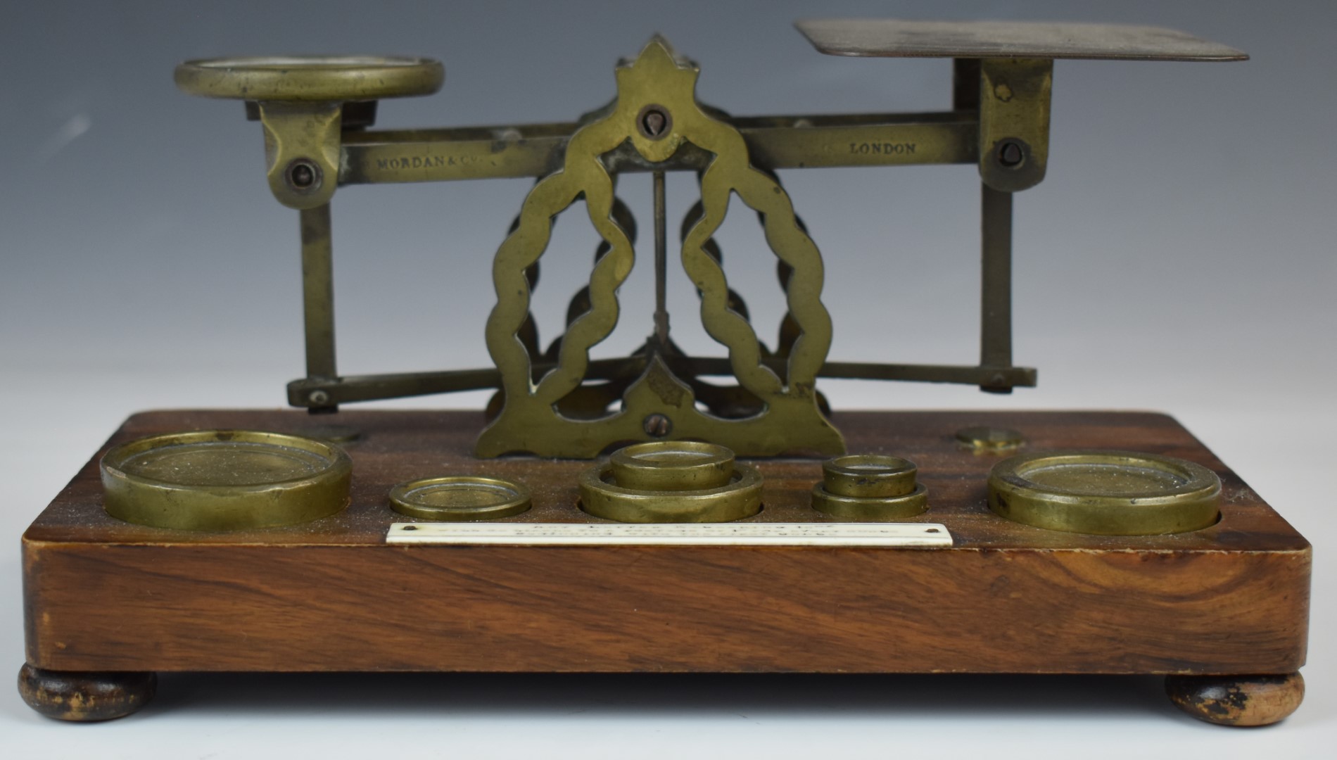 Mordan & Co. Victorian brass postage scales, on wooden base with weights and with postage rates to
