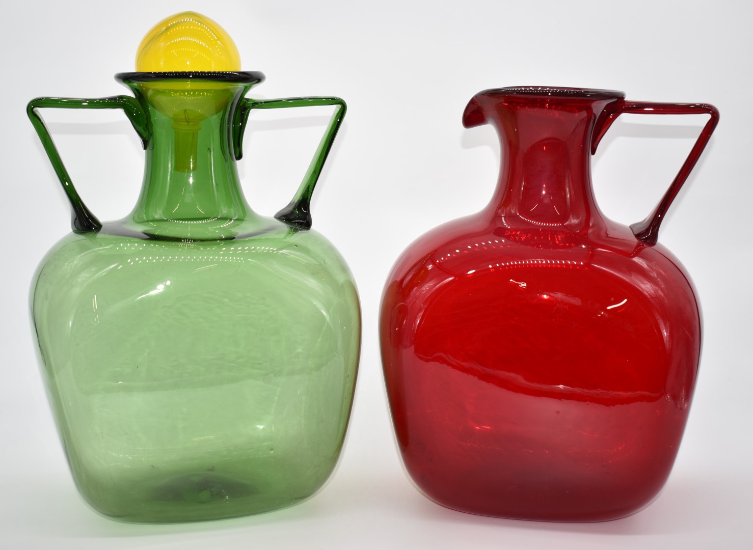 Two Polspotten jugs, one green with twin handles and yellow stopper the other red, tallest 43cm