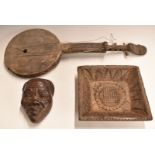 Three African carved wooden tribal items including a stringed instrument with mask decoration,