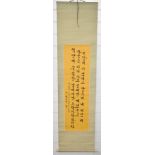 Korean scroll painting with black script on yellow ground, 135 x 33cm