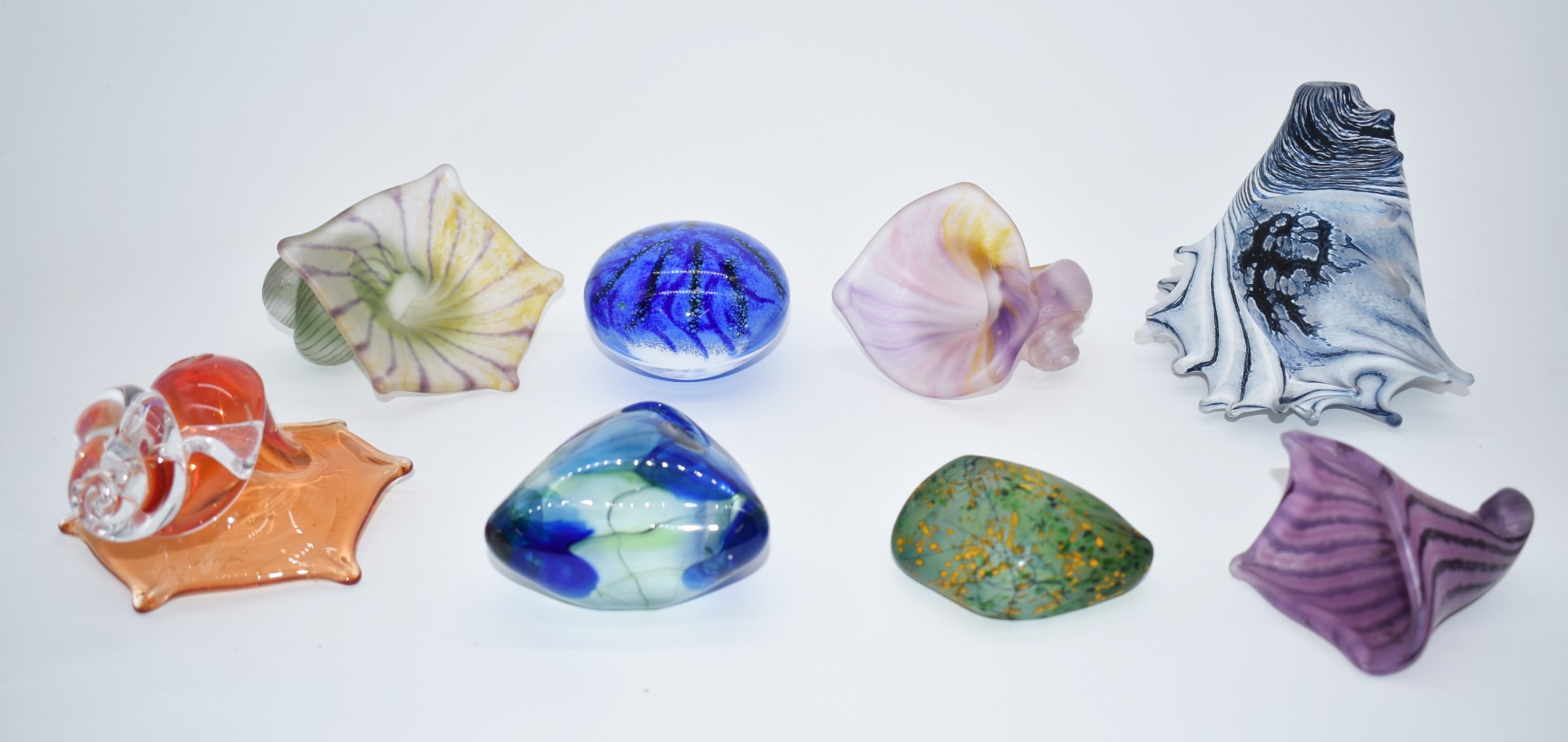 A collection of glass paperweights, pebbles and shells including Peter Layton and similar signed