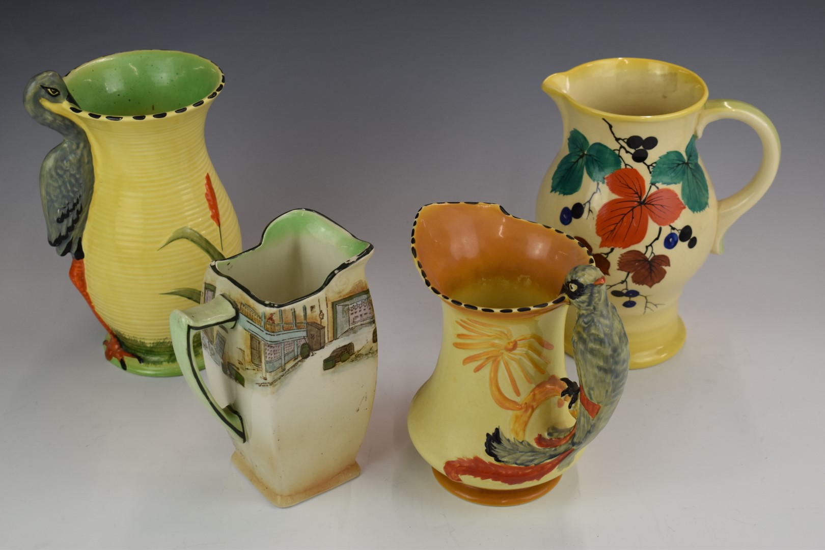 Art Deco and Series Ware jugs by Royal Doulton and two Burleigh Ware jugs with figural bird handles