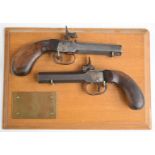 A pair of percussion hammer action pocket pistols each with shaped wooden grips and 3 inch smooth