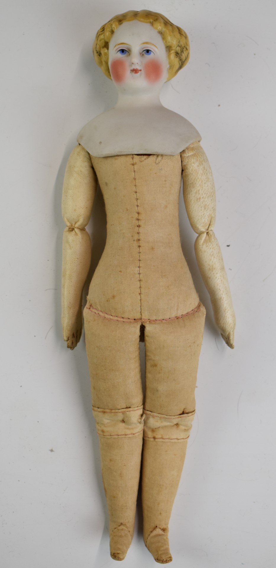 A 19thC bisque headed doll with painted features, cotton body and kid leather arms, 25cm tall.