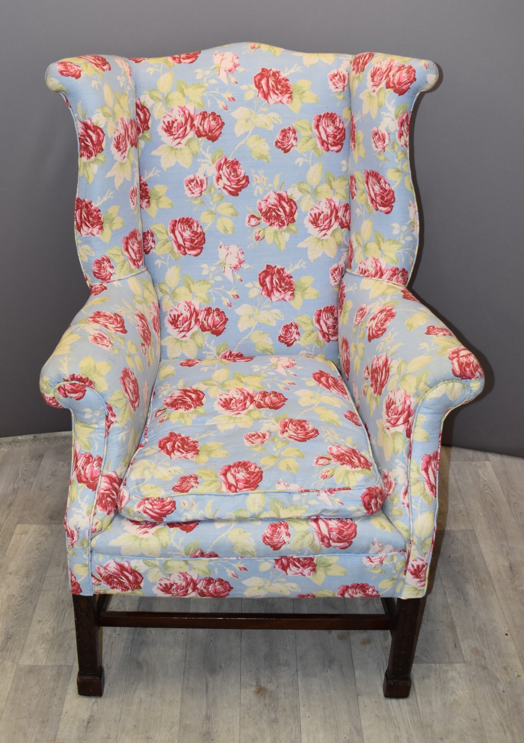 19thC wing back armchair with floral upholstery, raised on square legs with carved decoration, width