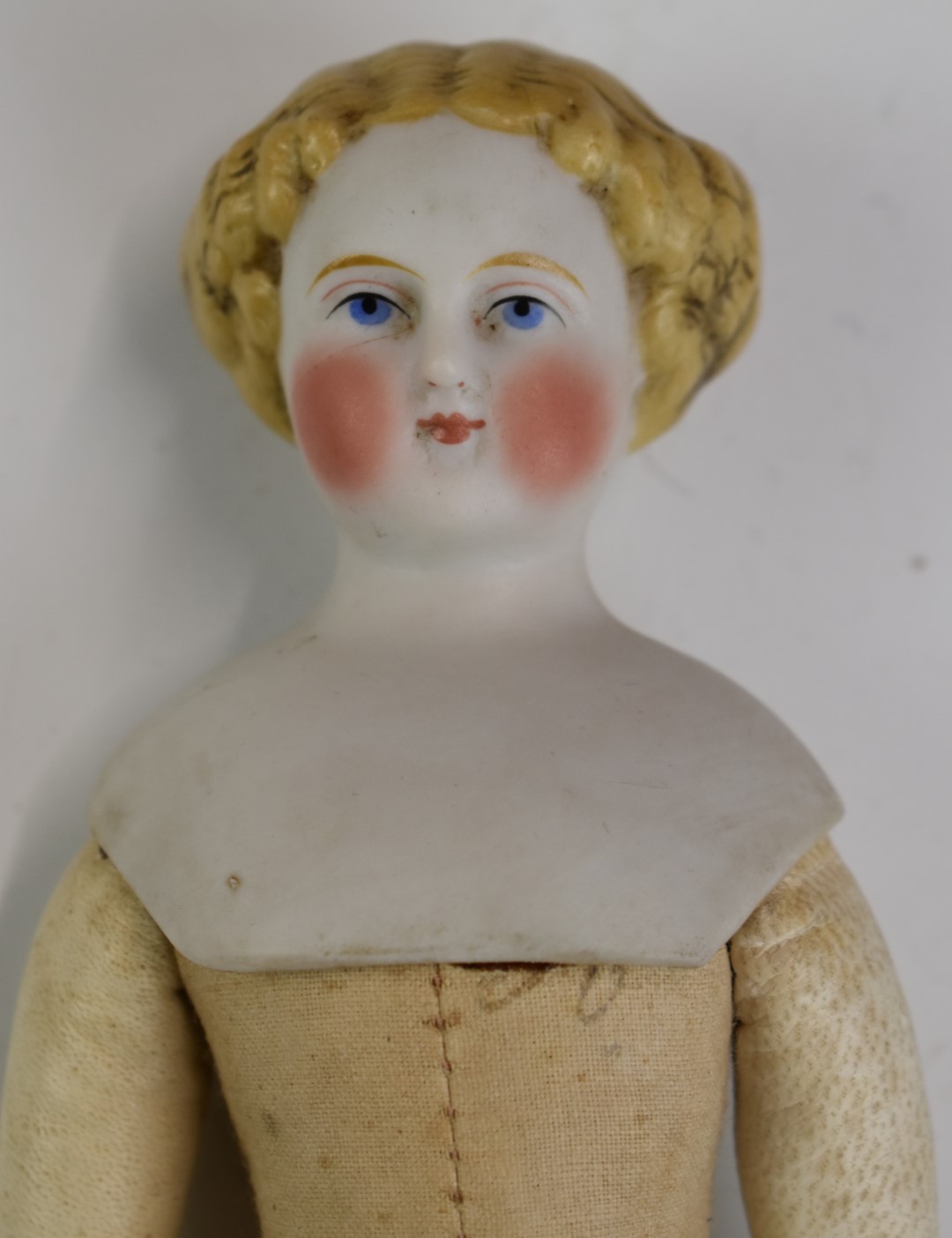 A 19thC bisque headed doll with painted features, cotton body and kid leather arms, 25cm tall. - Bild 2 aus 4