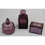 Three pieces of amethyst glass comprising a Heinrich Hoffman lidded box and scent bottle both with