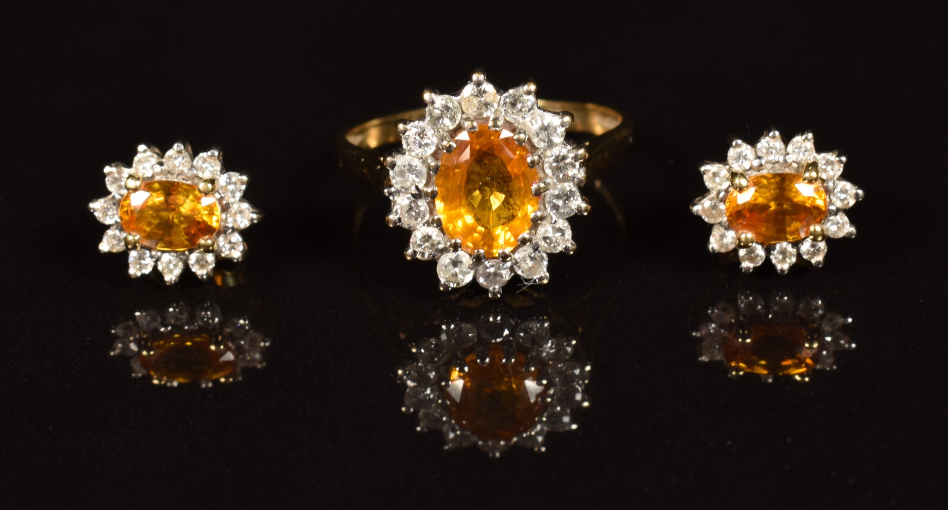 A 9k gold ring set with an oval cut orange sapphire surrounded by diamonds (size Q), with matching