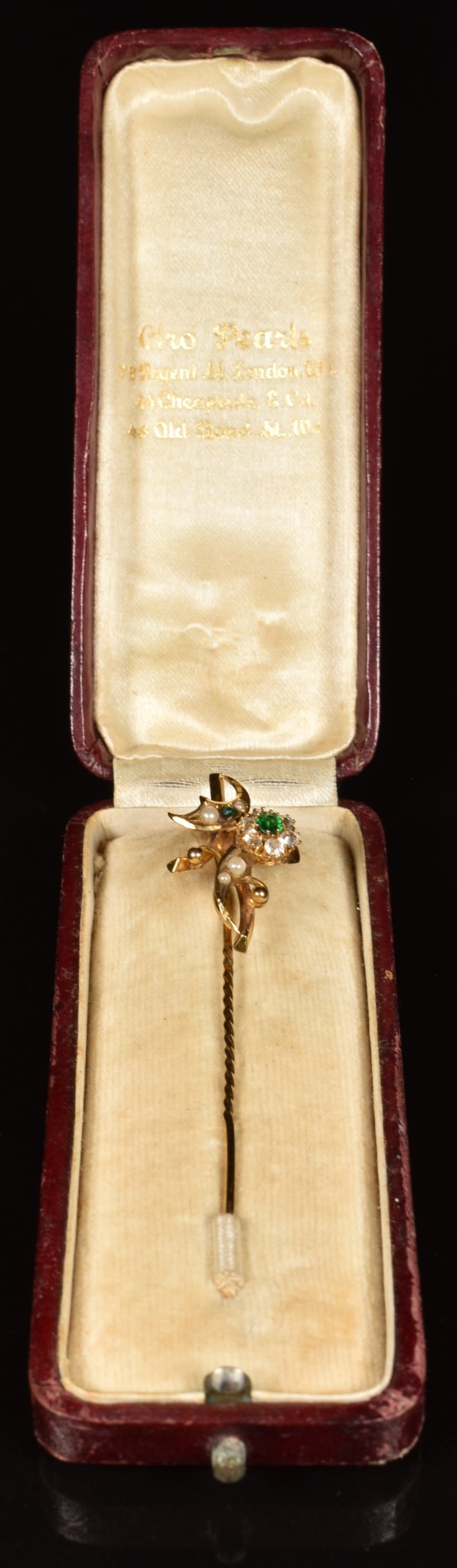 A yellow metal stick pin set with paste and faux pearls in a floral design, in vintage box