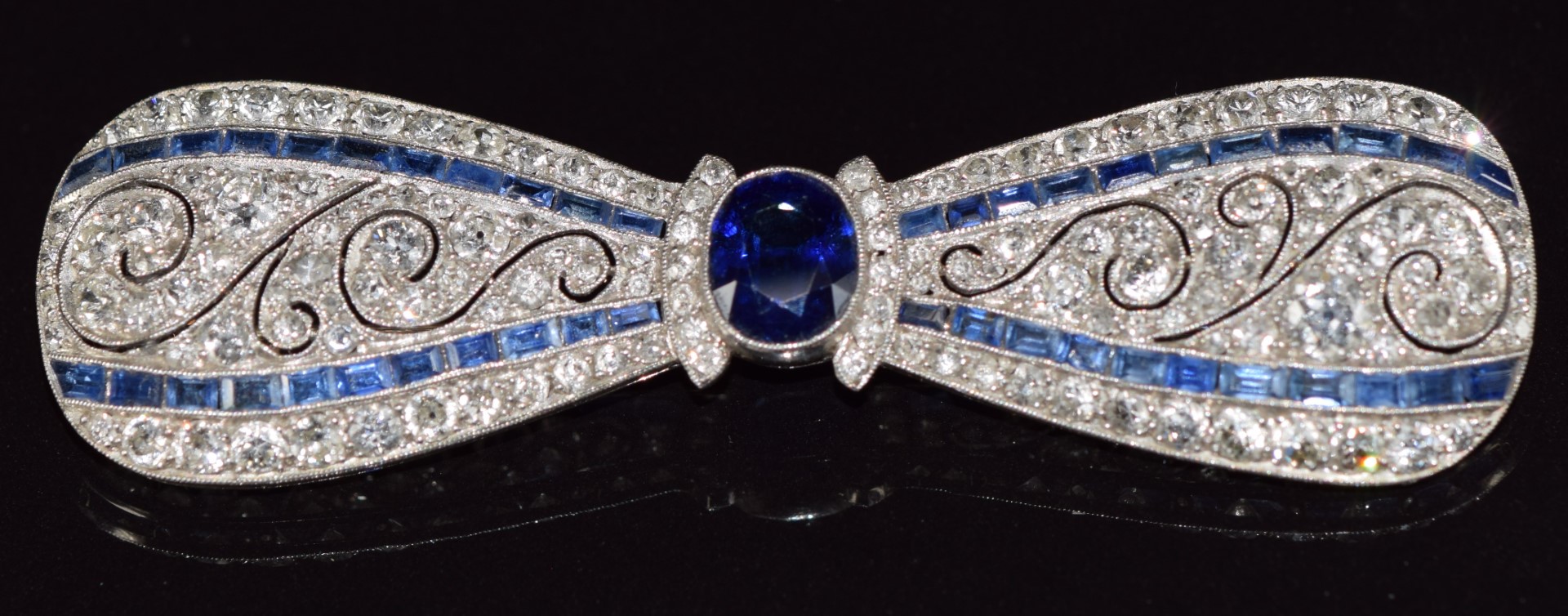 A c1915 platinum brooch in the form of a bow set with an oval cut sapphire measuring approximately - Image 2 of 7