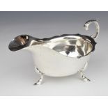 Edward VII hallmarked silver sauce boat with scroll handle, raised on three feet, Chester 1908,
